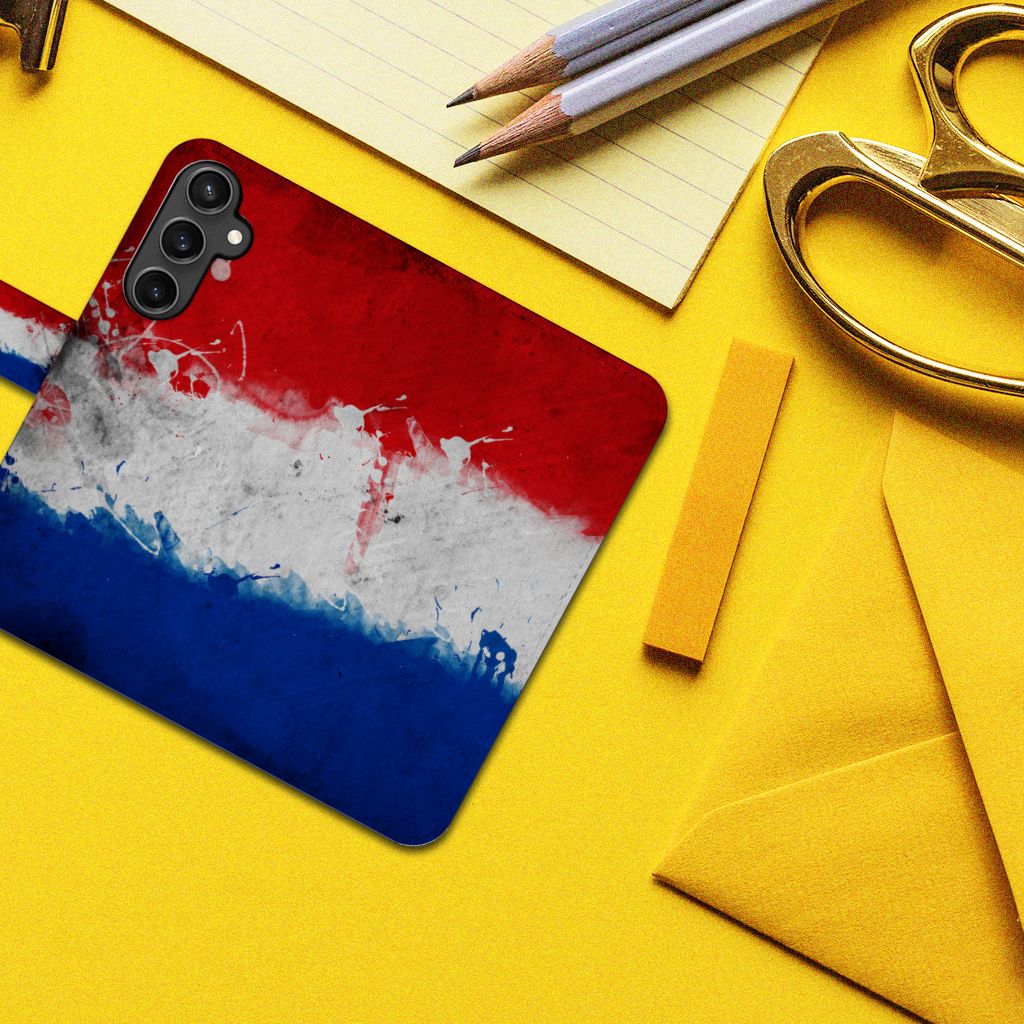 Samsung Galaxy S23 FE Bookstyle Case Nederland met artistiek ontwerp van de Nederlandse vlag op een bureau.
