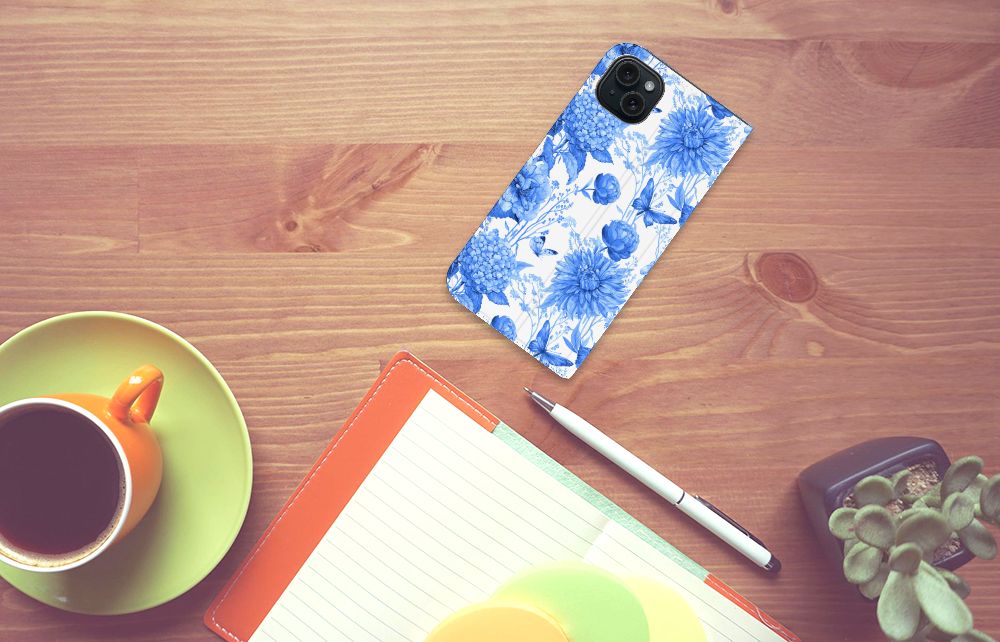 Smart Cover voor iPhone 15 Plus Flowers Blue op een houten tafel met een kopje koffie ☕ en notitieboek.