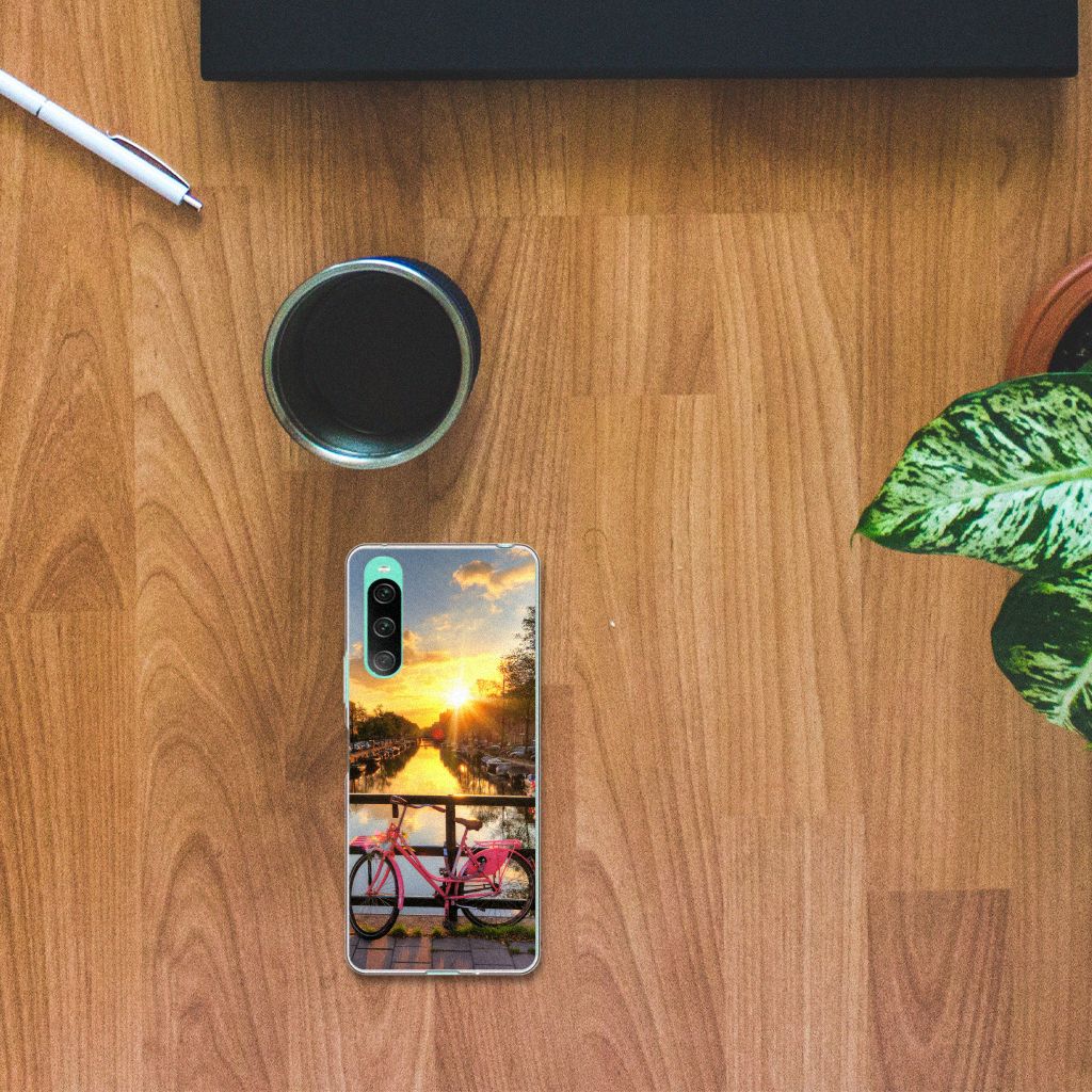Sony Xperia 10 V Siliconen Back Cover Amsterdamse Grachten met fiets en zonsondergang 🌅 op een houten tafel.