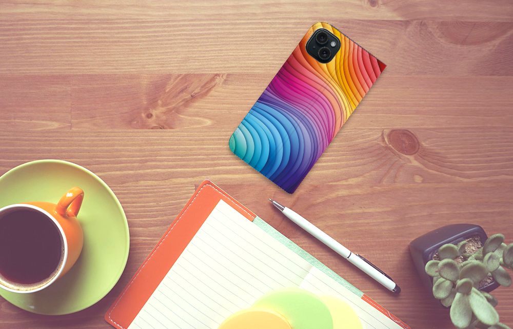 Stand Case voor iPhone 15 Plus Regenboog met kleurrijke golven op een houten tafel met een kop koffie ☕.
