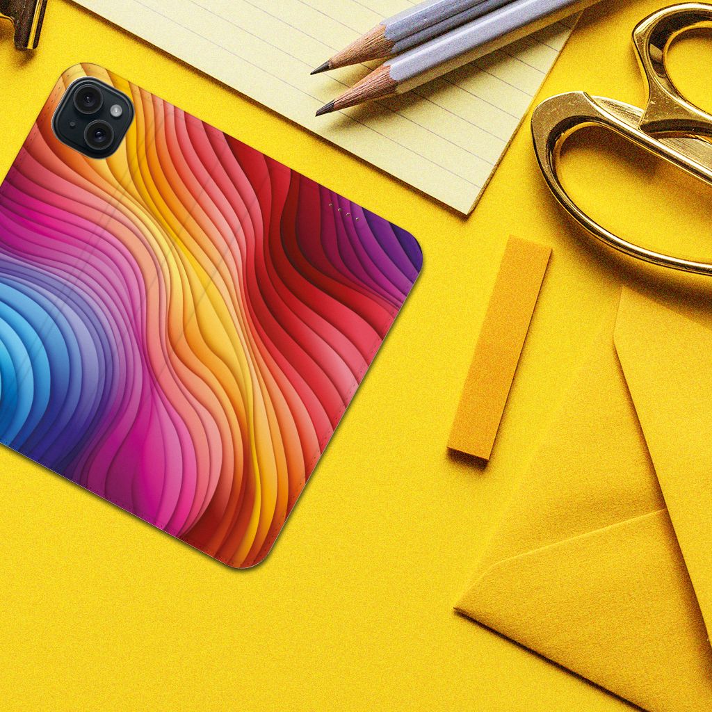 Stand Case voor iPhone 15 Plus Regenboog met kleurrijk golfpatroon op geel bureau.