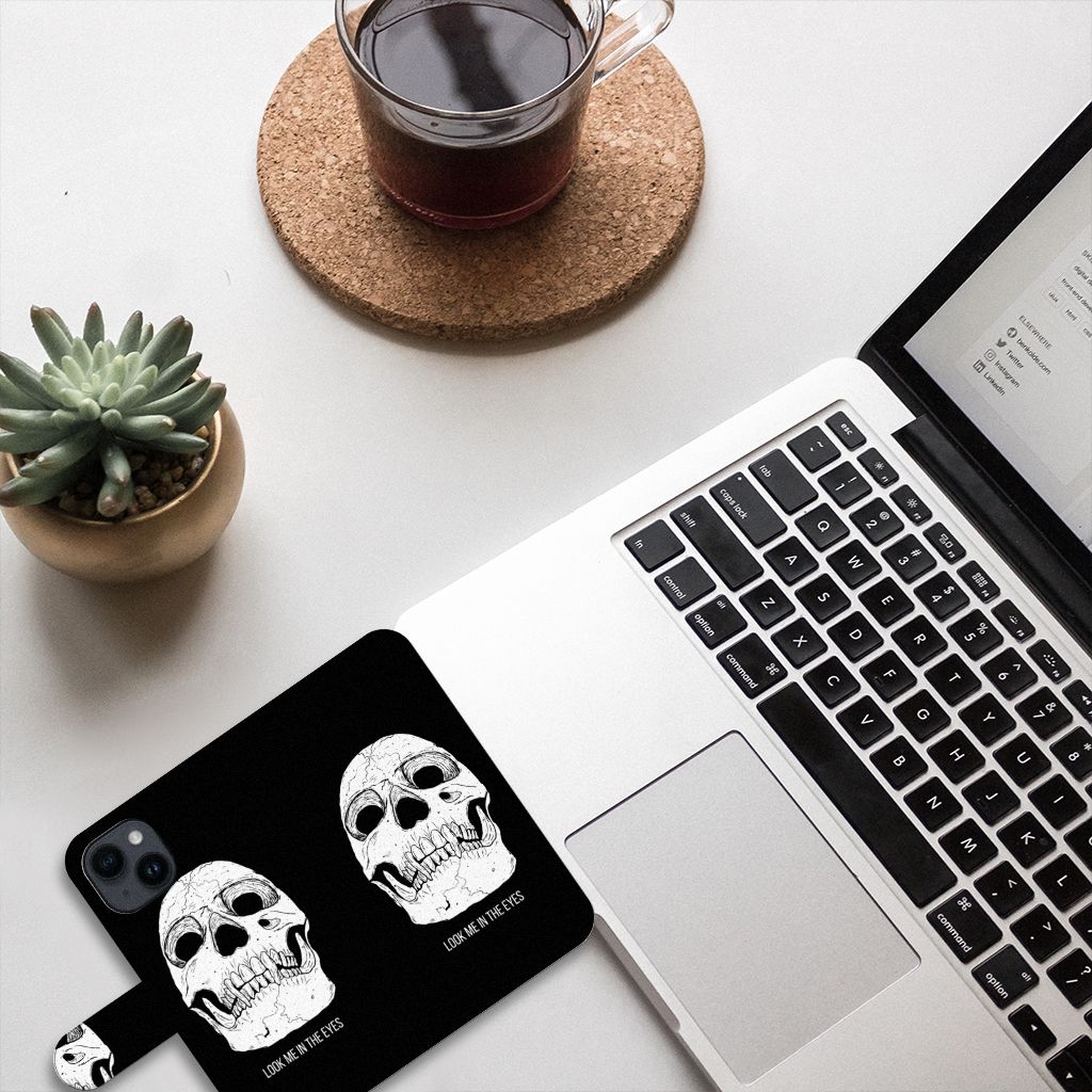 Telefoonhoesje met Naam iPhone 15 Skull Eyes op een bureau met een laptop en koffie.