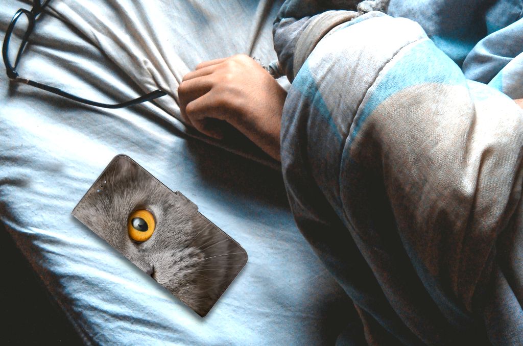 Telefoonhoesje met Pasjes OPPO A16/A16s/A54s Britse Korthaar op bed met een hand en een bril.