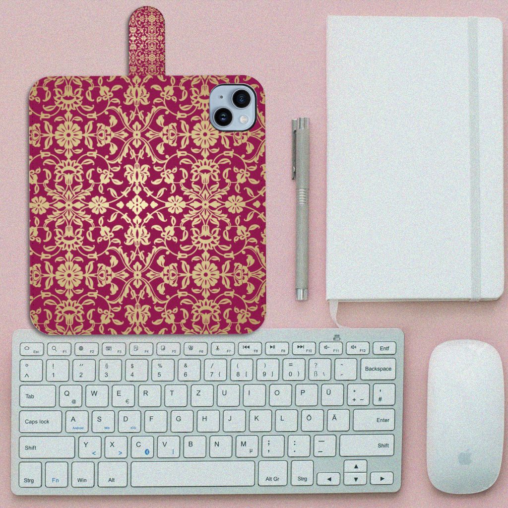 Wallet Case iPhone 15 Plus Barok Pink met sierlijk design op een bureau met toetsenbord en notitieboek.