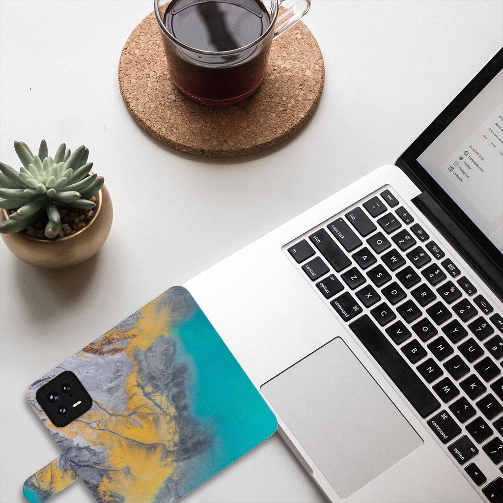Xiaomi 13 Bookcase Marble Blue Gold naast een laptop, perfect cadeau voor stijl en bescherming.