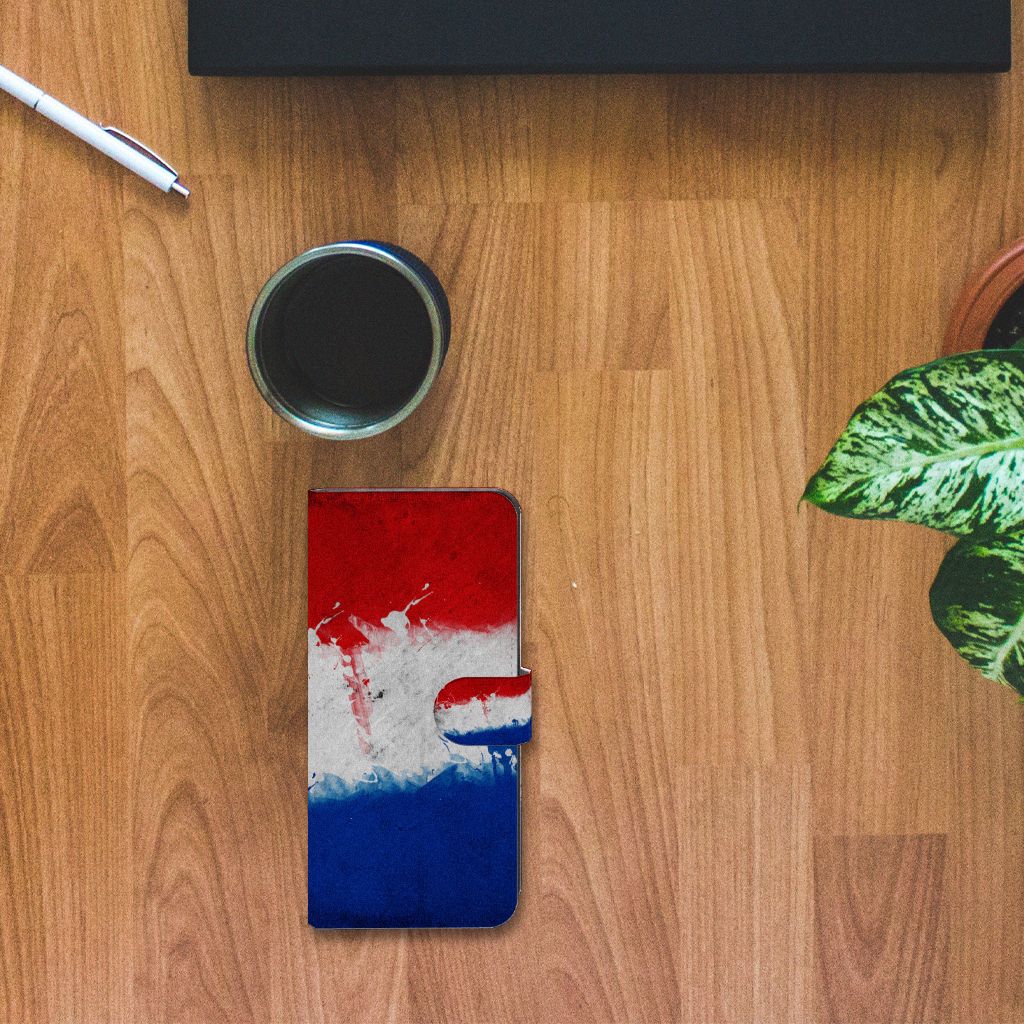 Xiaomi 13 Lite Bookstyle Case Nederland met artistieke Nederlandse vlag design op bureau met koffie en planten