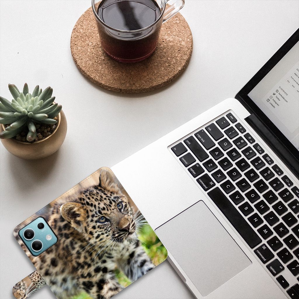 Xiaomi Redmi Note 13 5G Telefoonhoesje met Pasjes Baby Luipaard liggend op bureau met laptop en plant