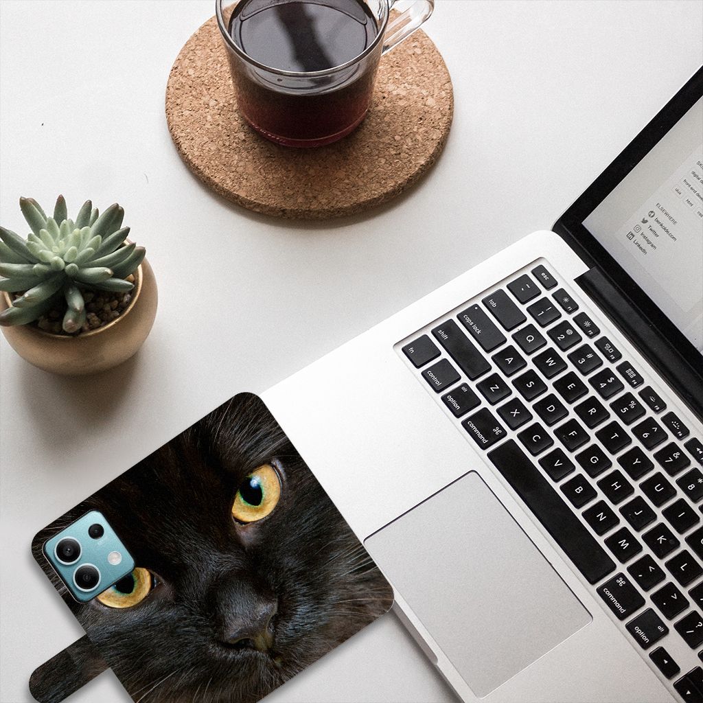 Xiaomi Redmi Note 13 5G Telefoonhoesje met Pasjes Zwarte Kat naast laptop met koffie, stijlvolle en duurzame bescherming.