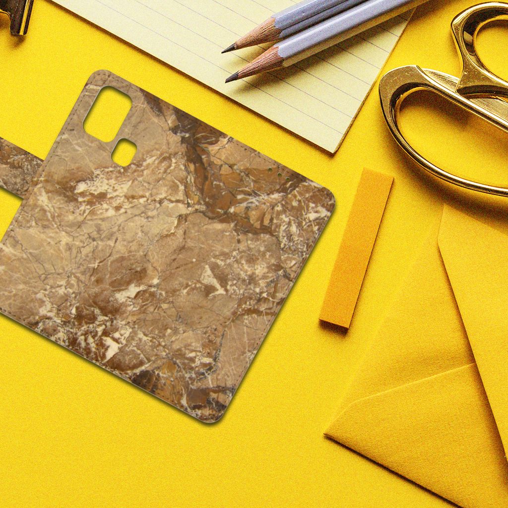 Samsung Galaxy M31 Bookcase Marmer Creme op een gele achtergrond met schrijfgerei.
