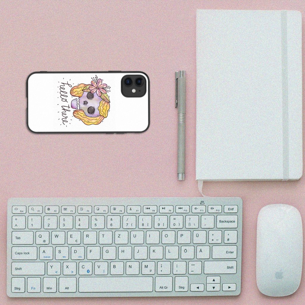 Telefoonhoesje iPhone 11 Boho Skull op een bureau met toetsenbord en notitieboek.
