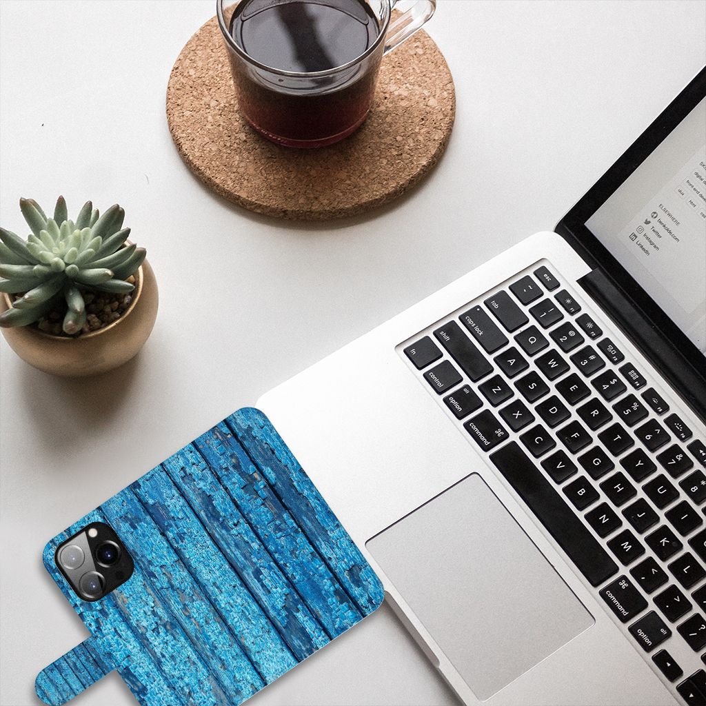 iPhone 14 Pro Book Style Case Wood Blue on a desk with a laptop and a cup of coffee, showcasing a beautiful wood design.