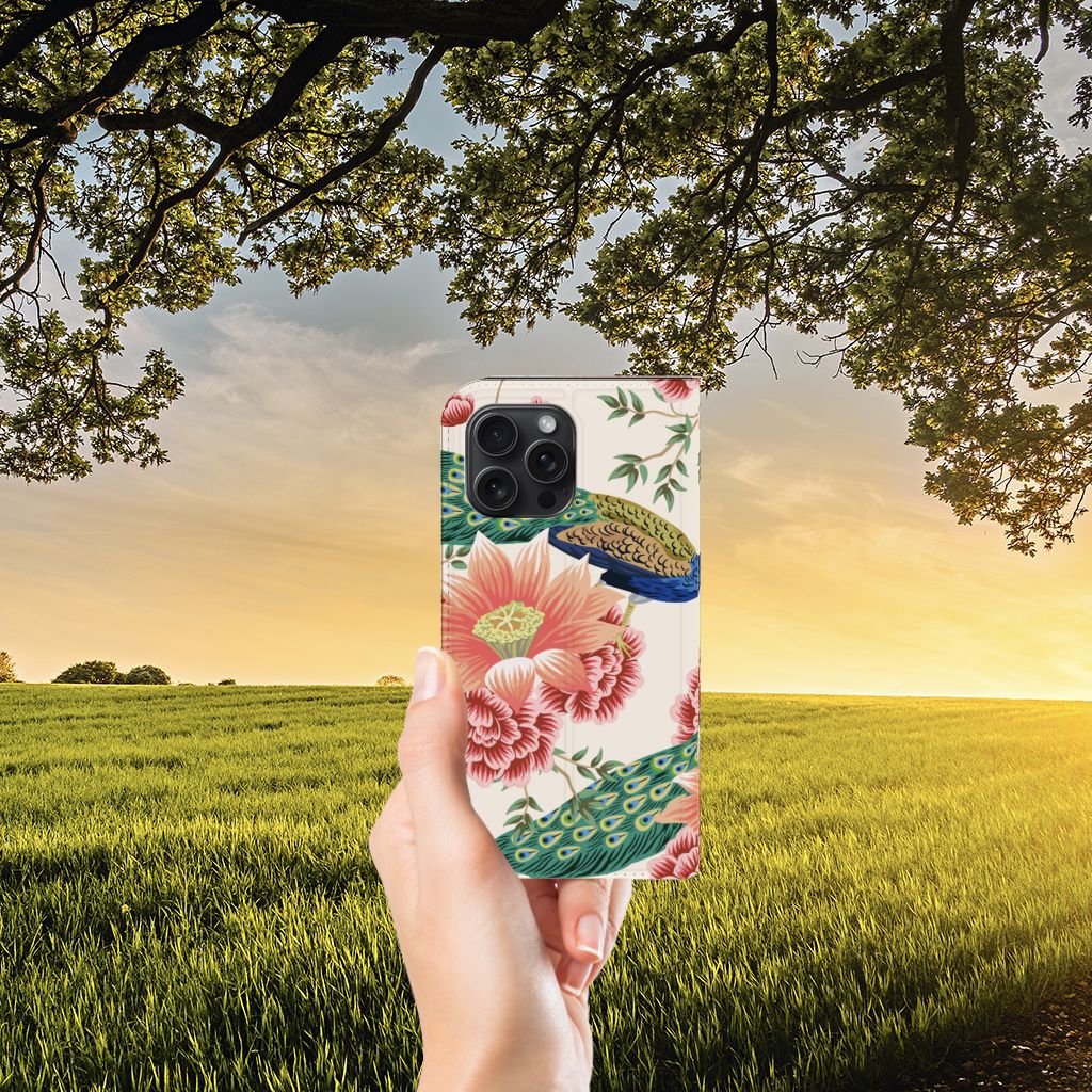 Hoesje maken voor iPhone 15 Pro Max Pink Peacock met kleurrijk pauwendesign en bloemen, vastgehouden in de natuur.