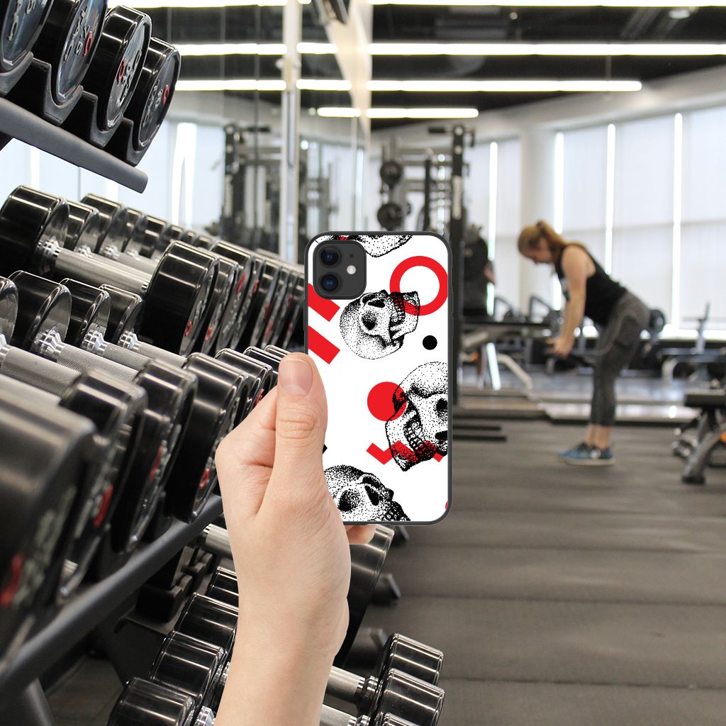 Telefoonhoesje iPhone 11 Skull Red in hand, met fitnessapparatuur op de achtergrond in een sportschool.