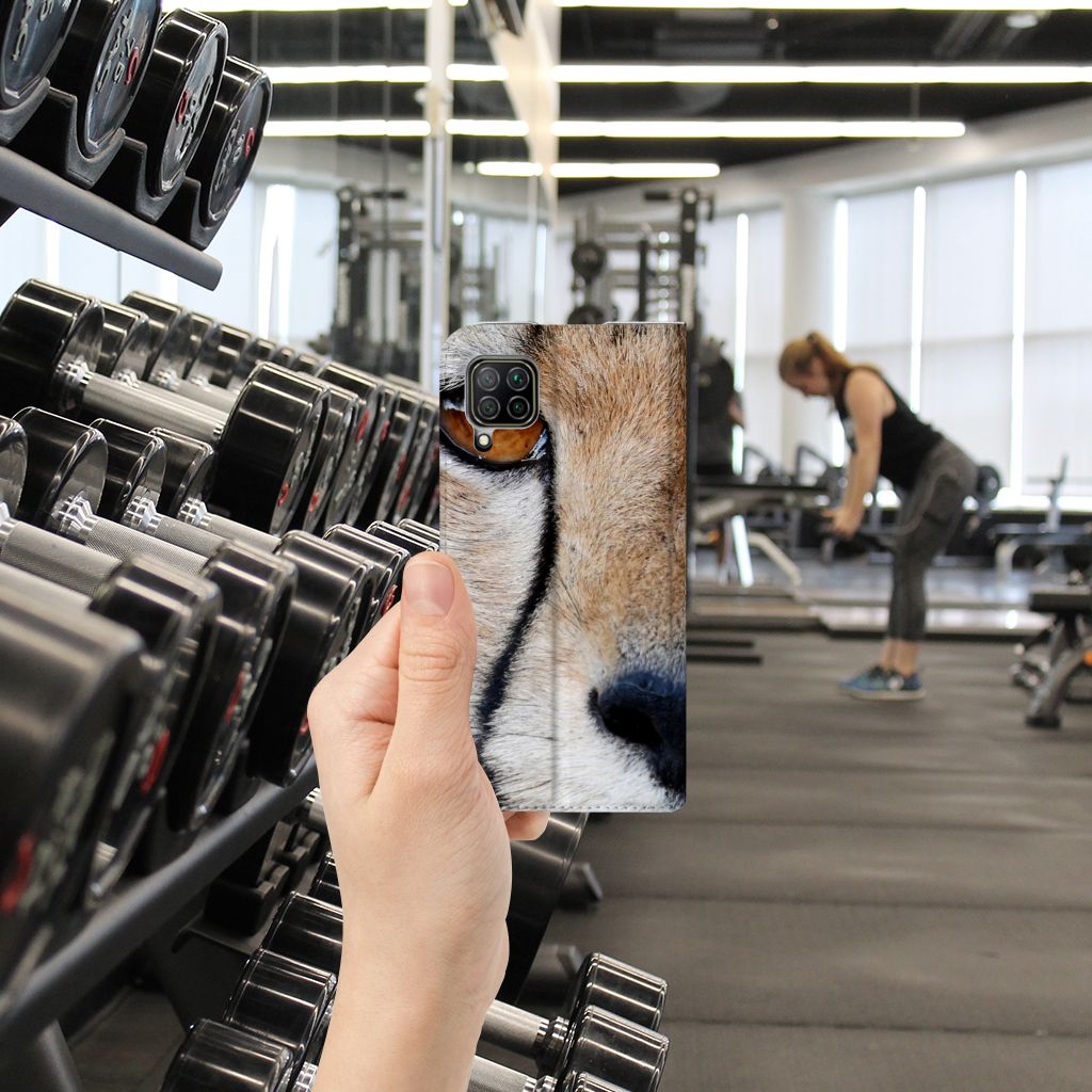 Huawei P40 Lite Hoesje maken Cheetah in een sportomgeving met gewichten en een vrouw die traint.