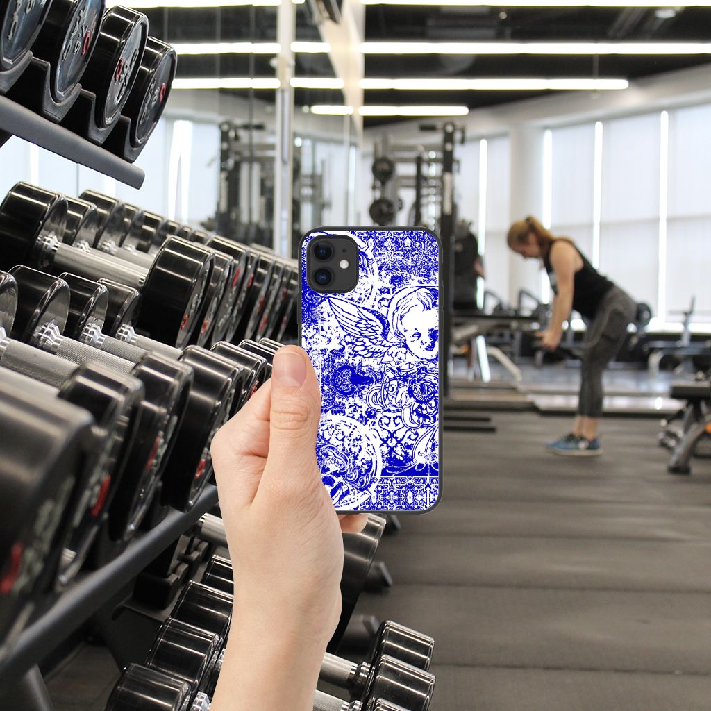 Telefoonhoesje iPhone 11 Angel Skull Blauw in hand, fitnessruimte met dumbbells en vrouw aan het trainen op de achtergrond.