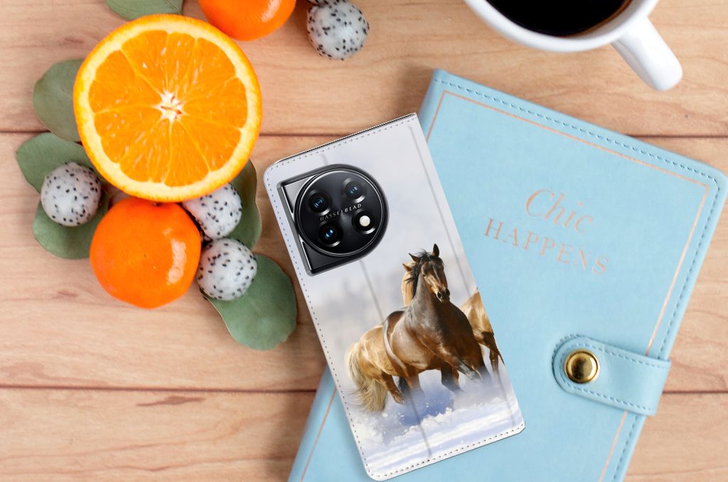 OnePlus 11 Hoesje maken Paarden met foto van rijdende paarden op een houten tafel met fruit en een notitieboek.