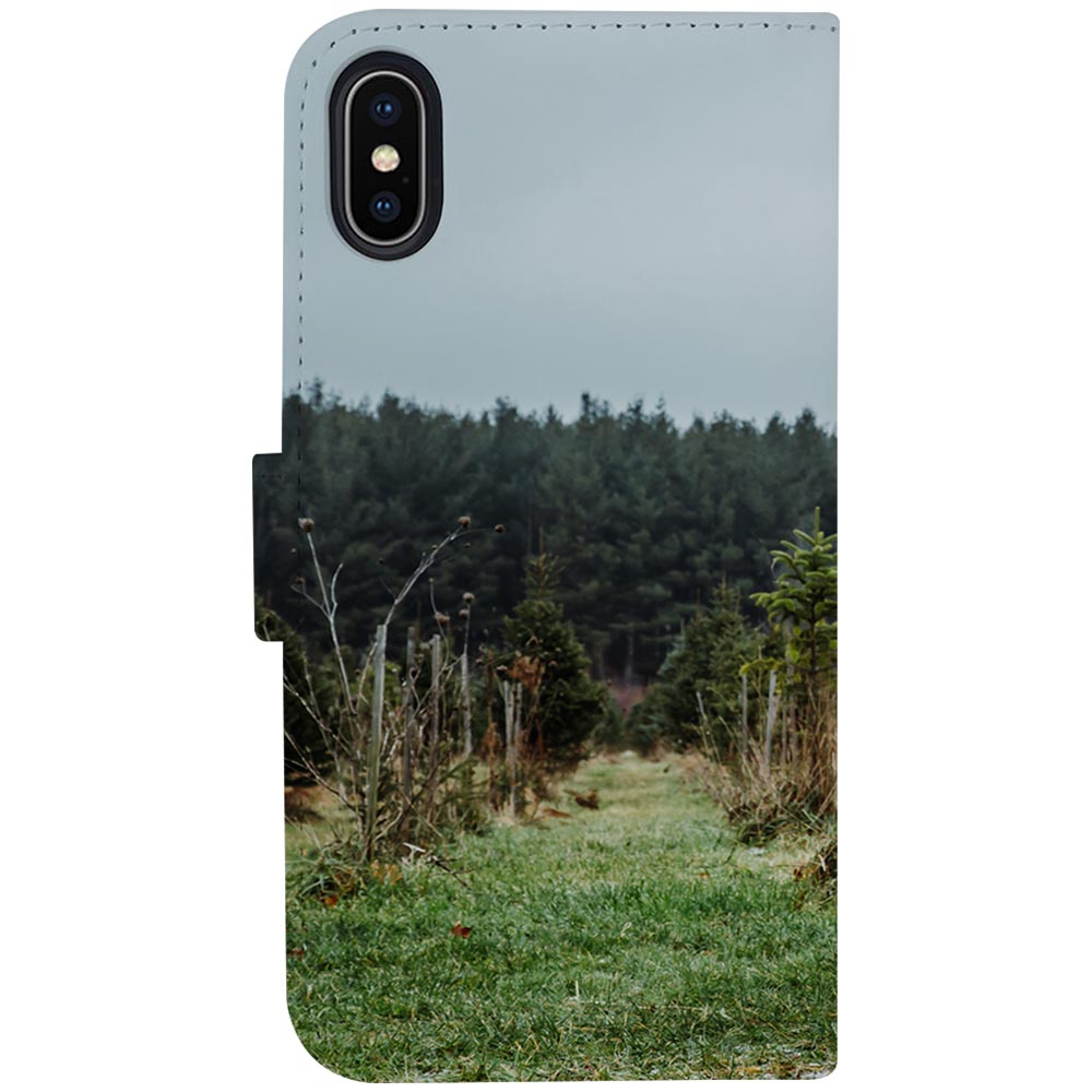 Achterkant iPhone X/Xs bookcase met camera-uitsparing linksboven en een graspad tussen de bomen