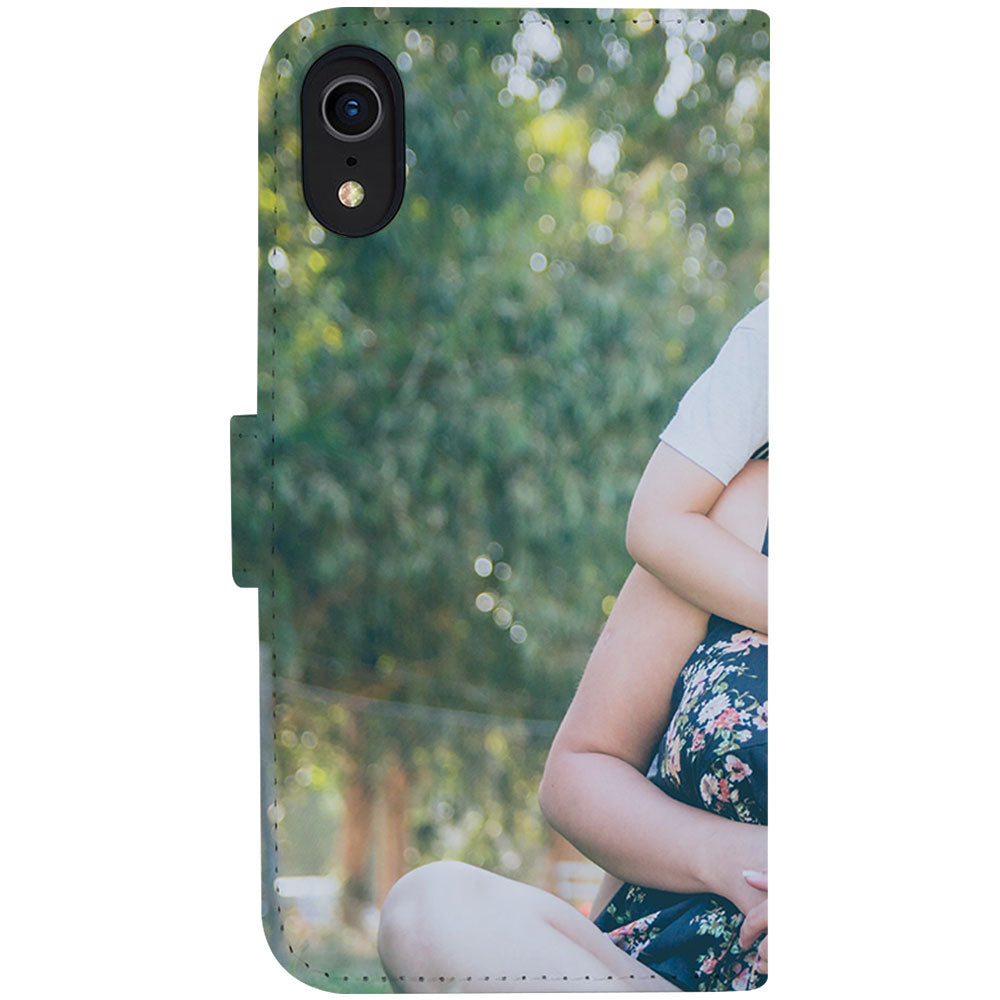 Achterkant van de iPhone Xr bookcase met camera-uitsparing linksboven, groene bomen en de arm van de moeder