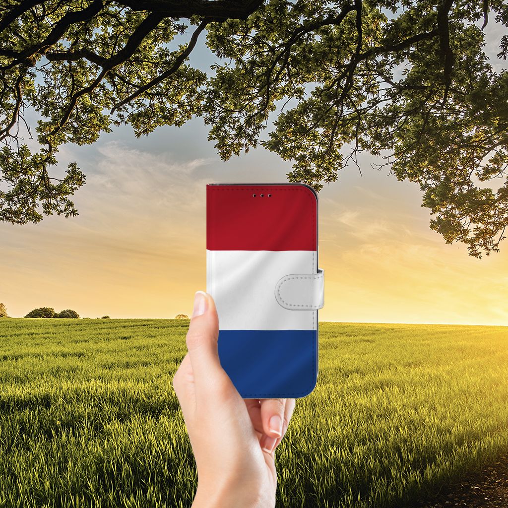 Apple iPhone 13 Bookstyle Case Nederlandse Vlag in hand met landschap op achtergrond.
