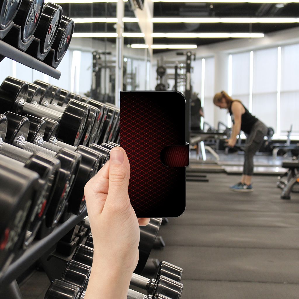 Samsung Galaxy S24 Telefoon Hoesje Geruit Rood in hand, met fitnessapparatuur op de achtergrond.