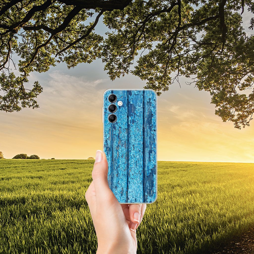 Samsung Galaxy A14 5G Bumper Hoesje Wood Blue met afgebladderd blauw hout in een groene omgeving