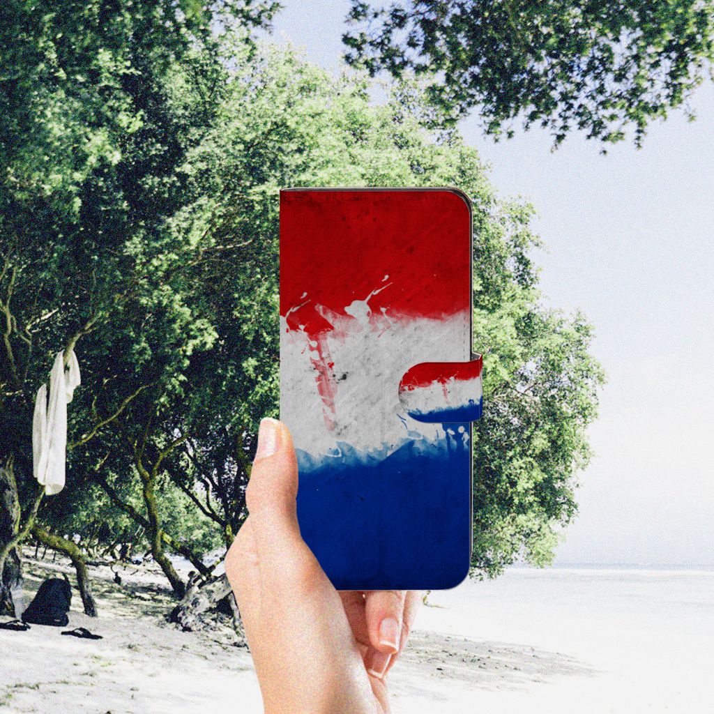 OPPO A98 5G Bookstyle Case Nederland met artistiek ontwerp van de Nederlandse vlag, vastgehouden bij het strand.