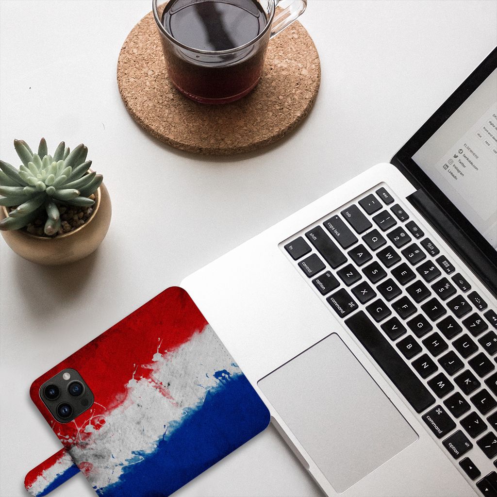 iPhone 15 Pro Bookstyle Case Nederland met ontwerp van de Nederlandse vlag, naast laptop en plant op bureau.