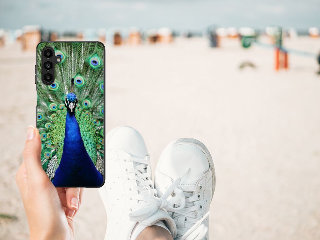 Samsung Galaxy A14 5G Dierenprint Telefoonhoesje Pauw in de hand met sneakers op een strandachtergrond.