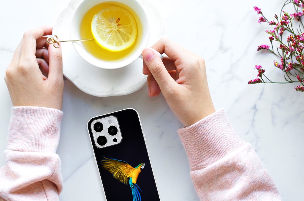 iPhone 15 Pro Max TPU Hoesje Papegaai met een kleurrijke print op een zwarte achtergrond en een kopje thee.