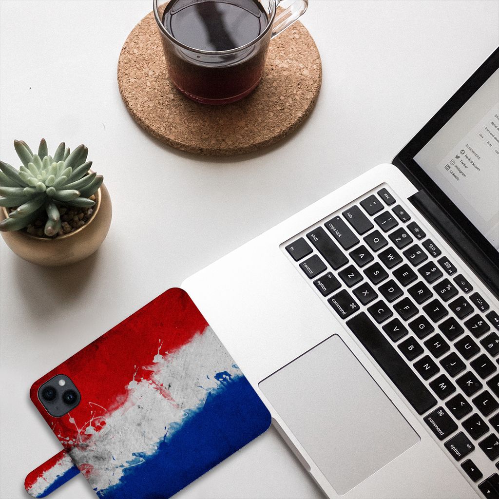 iPhone 15 Bookstyle Case Nederland met artistiek ontwerp van de Nederlandse vlag op een bureau.