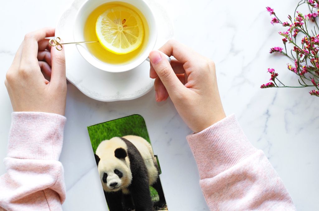 iPhone 15 Telefoonhoesje met Pasjes Panda op een marmeren tafel met een kopje thee.