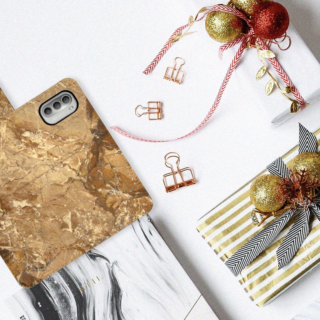 Motorola Moto G51 5G Bookcase Marmer Creme op een tafel met cadeauverpakkingen en decoraties.