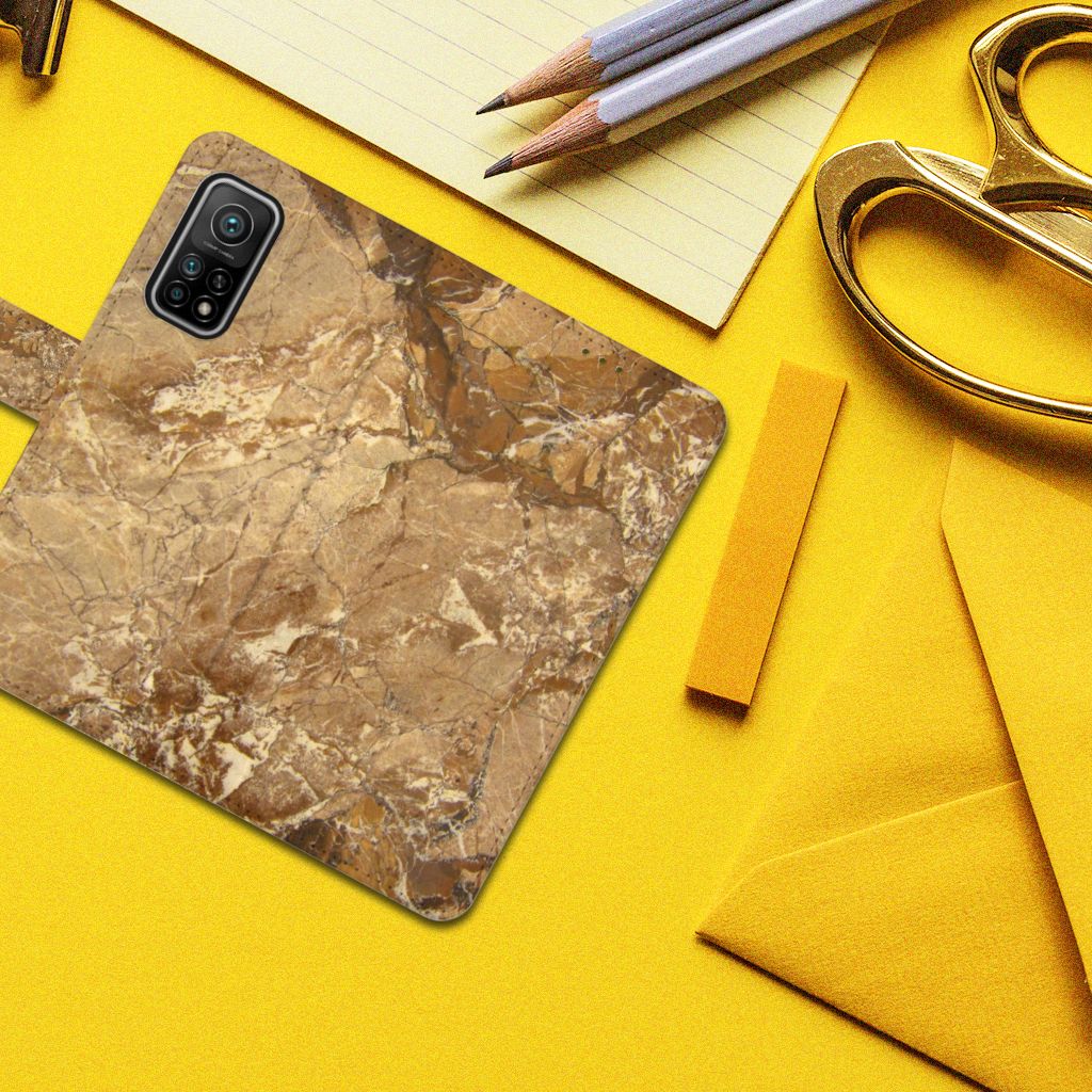 Xiaomi Mi 10T Pro | Mi 10T Bookcase Marmer Creme op een gele achtergrond met kantoorbenodigdheden.