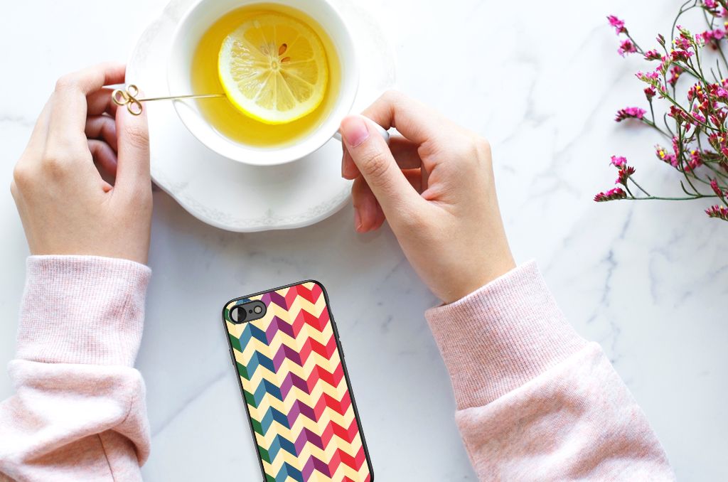 Person holding a cup of tea beside an iPhone SE 2022 | SE 2020 | 7/8 Back Case Zigzag Multi Color on a table.