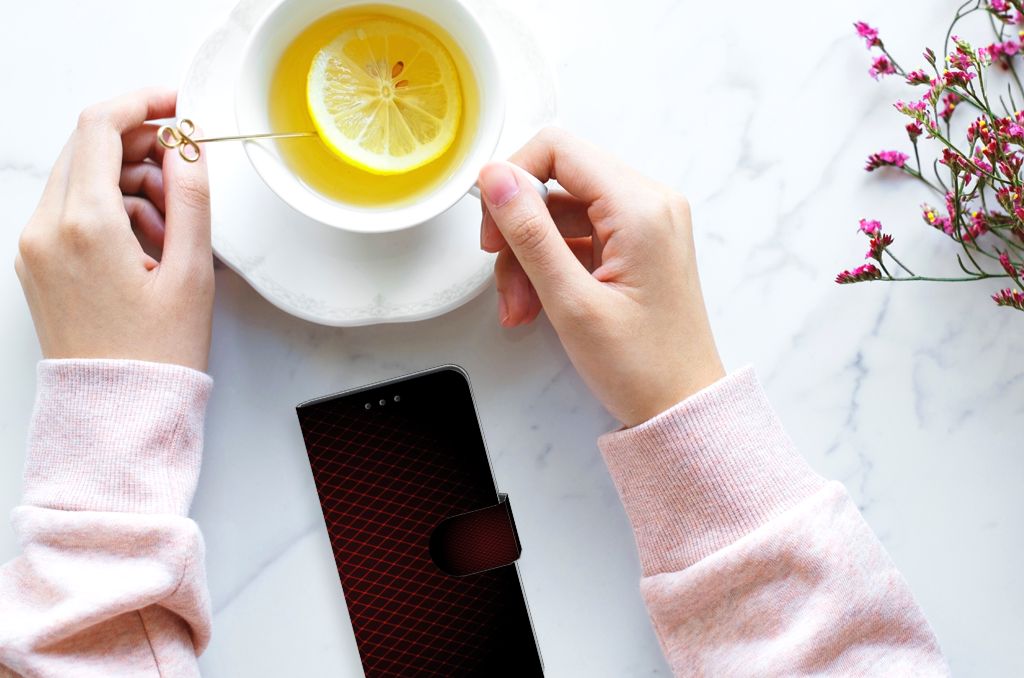 Huawei P40 Telefoon Hoesje Geruit Rood met een vrouwelijk hand die een kopje thee vasthoudt op een marmeren tafel.