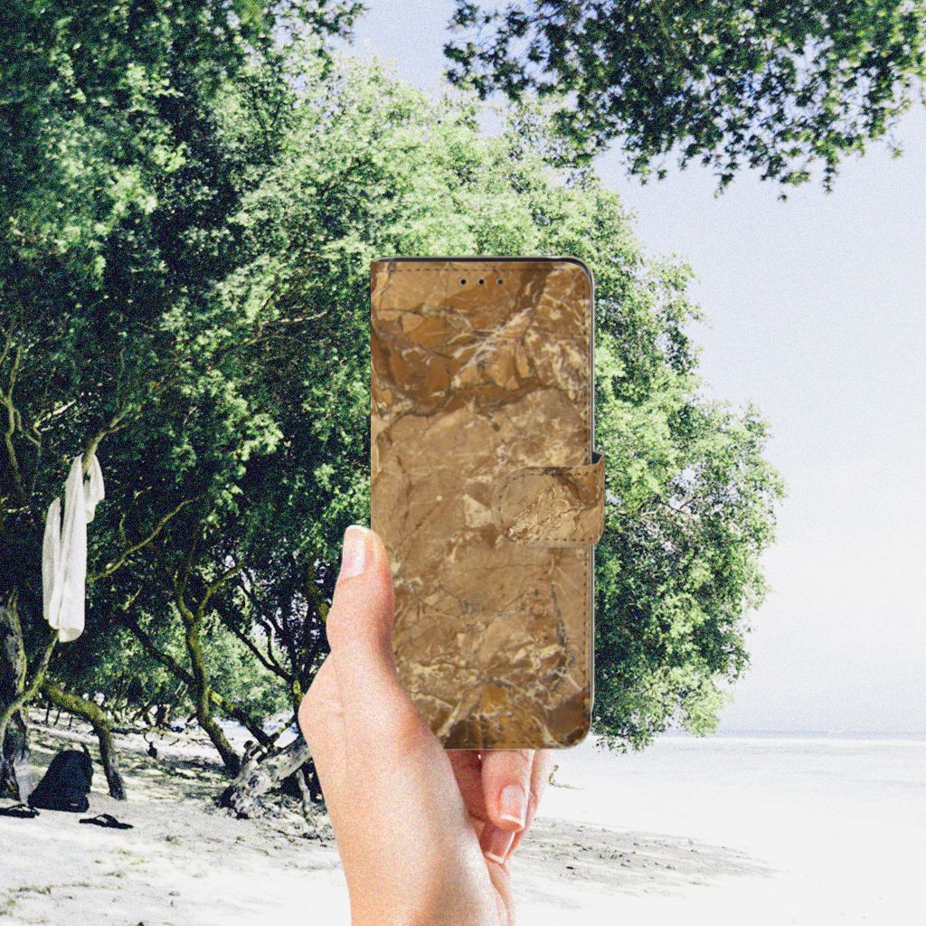 Sony Xperia L4 Bookcase Marmer Creme weergegeven op een hand op het strand tussen bomen.