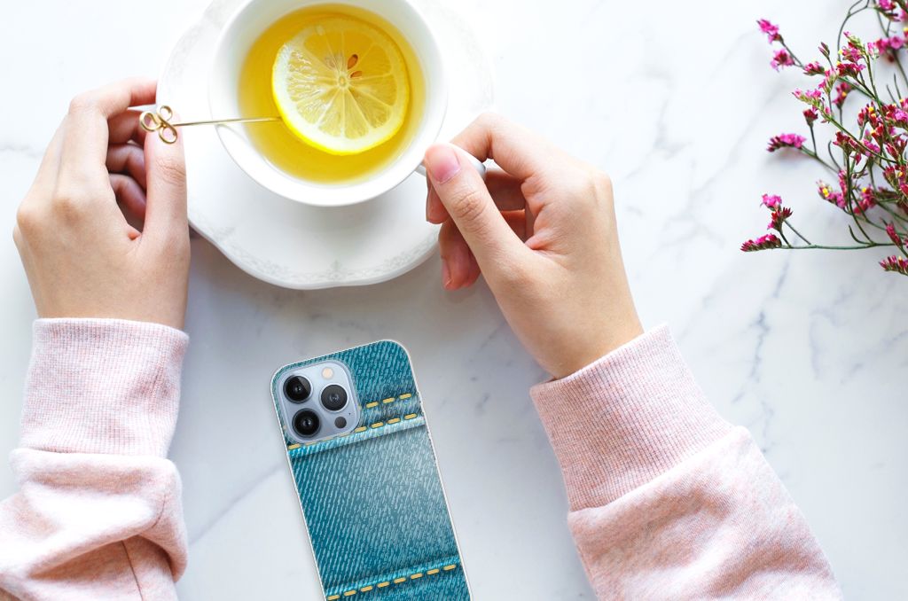 Apple iPhone 13 Pro Silicone Back Cover Jeans met een fris drankje en een hand op een marmeren tafel.