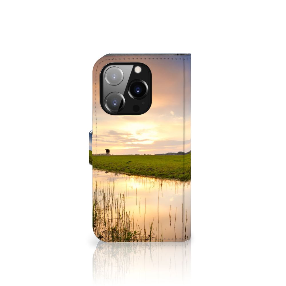iPhone 14 Pro Telefoonhoesje met Pasjes Koe, vrolijk design met koe in een weiland en zonsondergang.