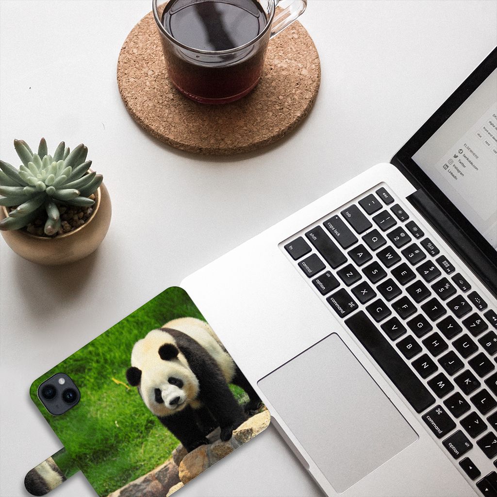 iPhone 15 Telefoonhoesje met Pasjes Panda ligt naast laptop en plant op bureau.