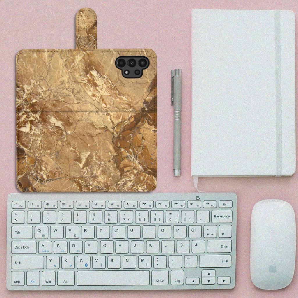 Samsung Galaxy A13 (4G) Bookcase Marmer Creme op een bureau met toetsenbord en accessoires.