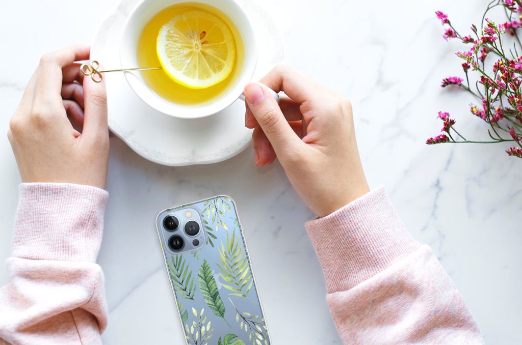 Apple iPhone 13 Pro TPU Case Leaves met een groen bladerenpatroon, geplaatst naast een kopje thee met citroen 🍋.