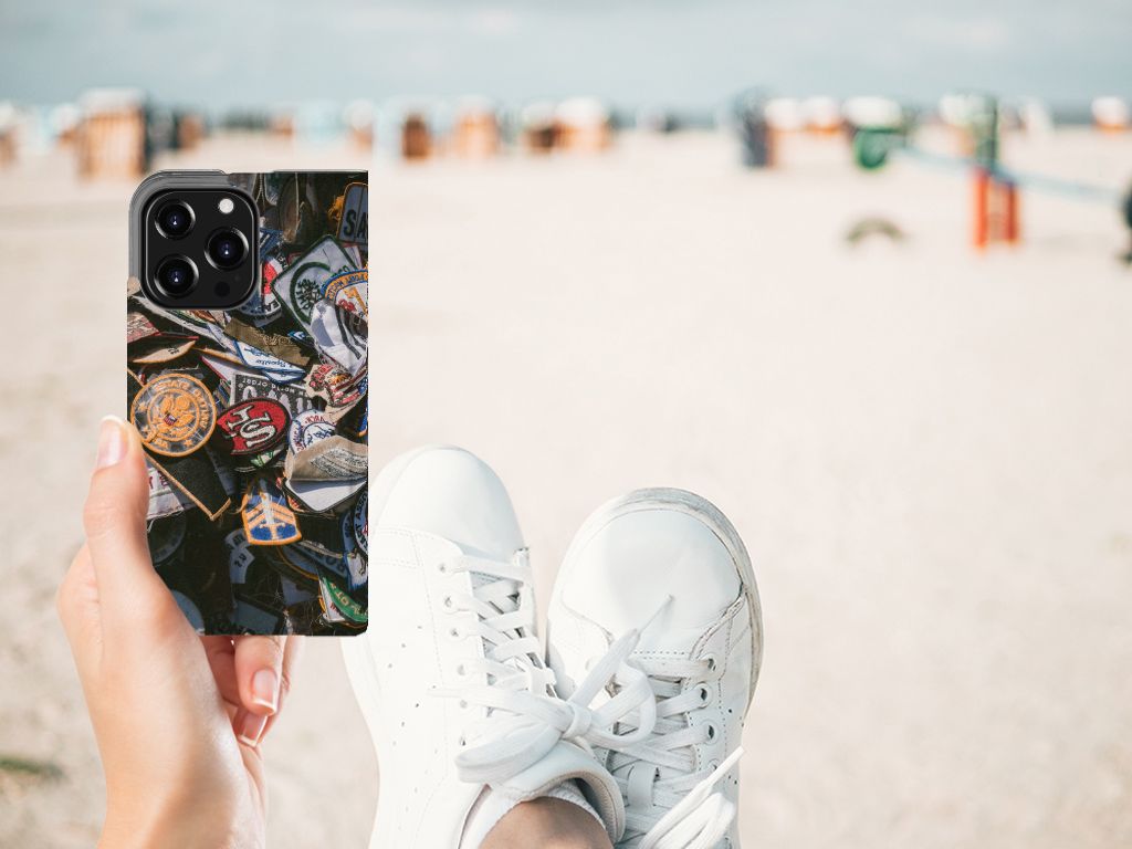 iPhone 13 Pro Stand Case Badges met kleurrijke badges op een hand die een voet op het zand plaatst 🏖️.