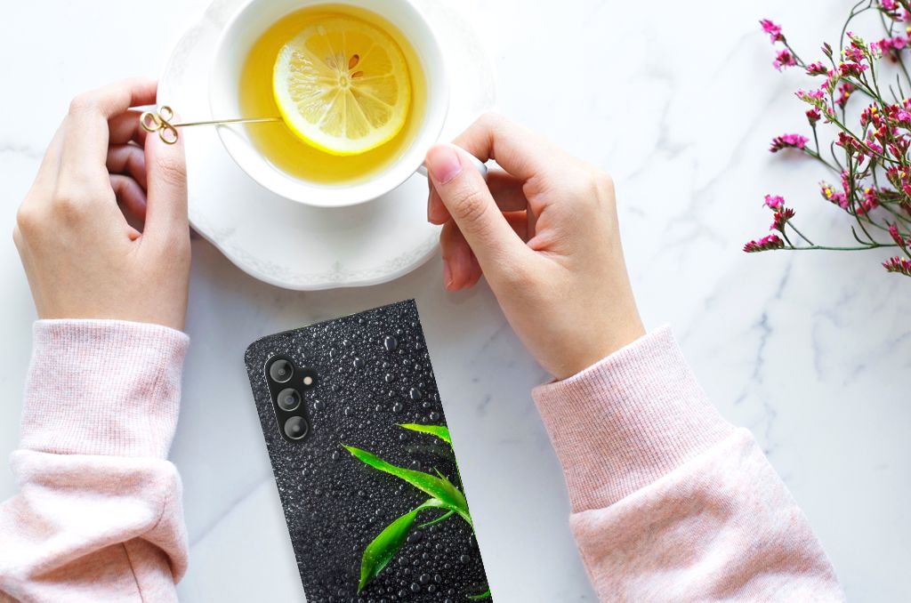 Samsung Galaxy A14 5G Smart Cover Orchidee met een drinkkopje en bloemen op een marmeren tafel.
