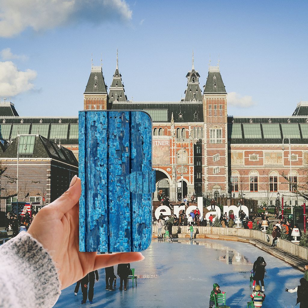 iPhone 13 Pro Max Book Style Case Wood Blue held in front of Amsterdam ice rink with historic buildings in background.