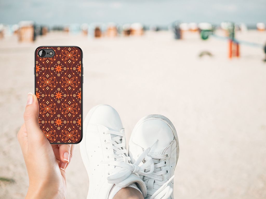 iPhone SE 2022 | SE 2020 | 7/8 Back Case Batik Brown displayed on a beach with a person's feet in white sneakers.