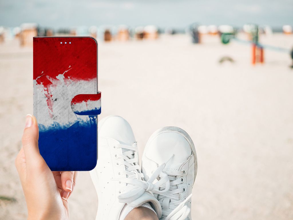 Person holding OPPO A74 4G Bookstyle Case Nederland with Dutch flag design at the beach.