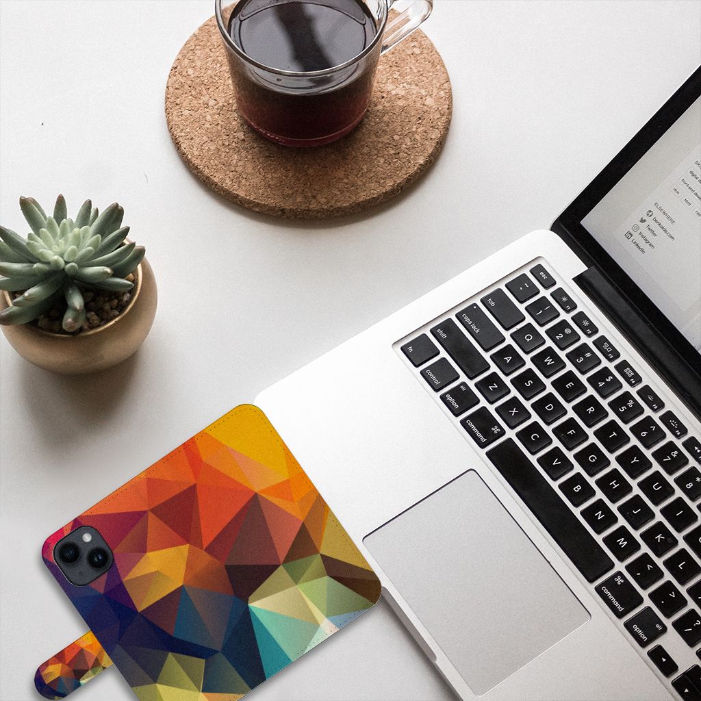 iPhone 15 Book Case Polygon Color met kleurrijk geometrisch ontwerp op een bureau met laptop en planten.