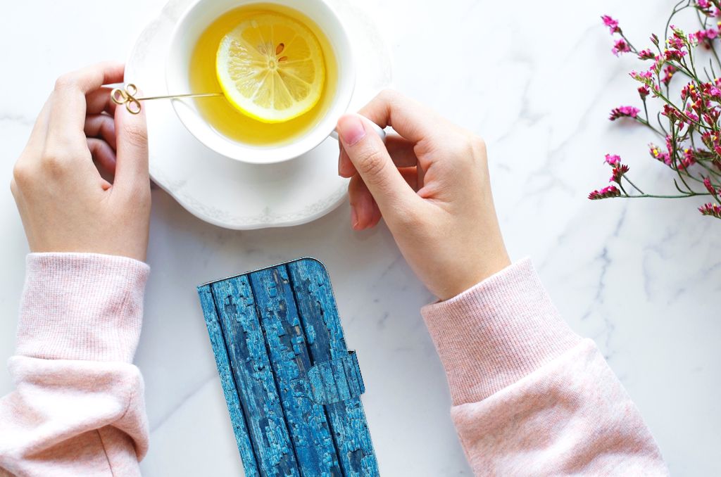 iPhone 15 Book Style Case Wood Blue naast een thee met citroen en bloemen, perfect voor stijlvolle bescherming.