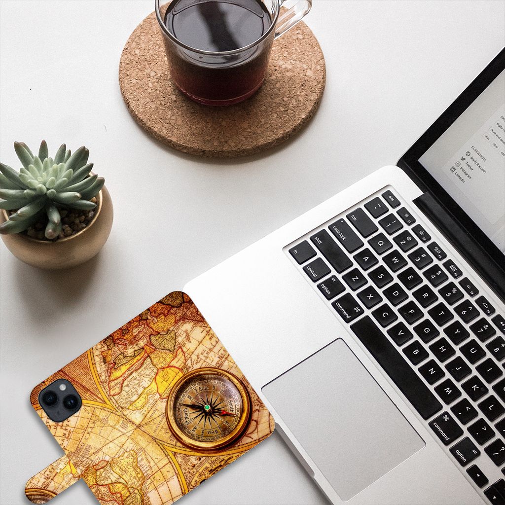 iPhone 15 Flip Cover Kompas met wereldkaart en kompas op een bureau naast een laptop en plant.