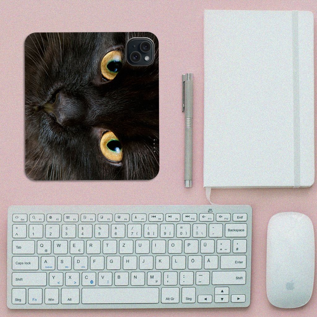 iPhone 15 Hoesje maken Zwarte Kat met close-up van zwarte kat's gezicht op bureau met toetsenbord en notitieboek.